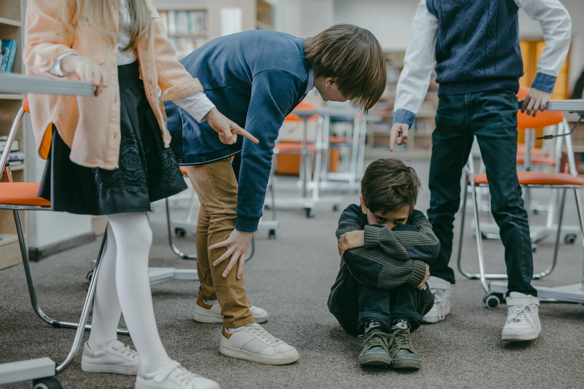 A group of children in a classroom displaying bullying behavior towards a peer.