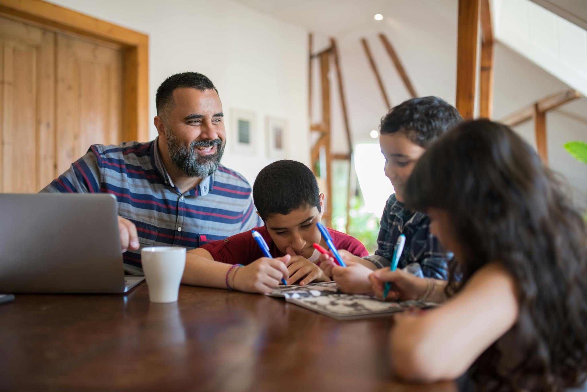 A joyful father spending quality time helping his children with a creative project indoors.